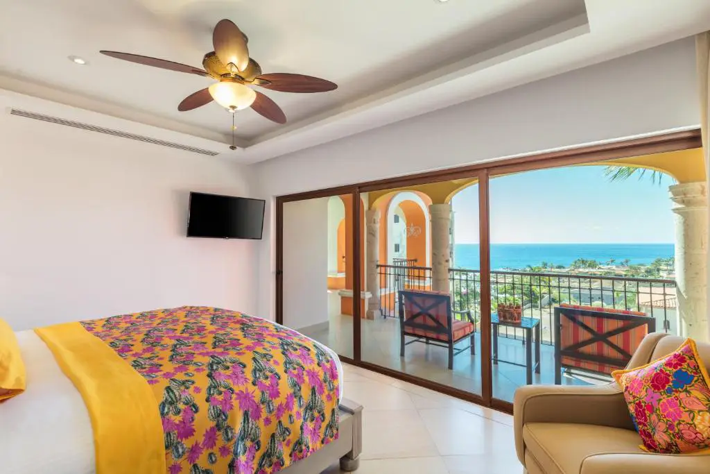 Suite de lujo con balcón y vista al océano en hotel de Los Cabos, decorada con colores vibrantes y confort exclusivo de Royal Beach Paradise.