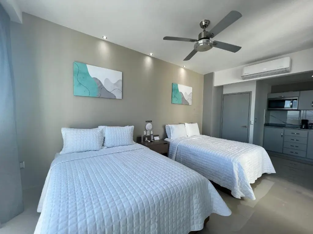 Suite doble moderna con dos camas, decoración minimalista y vista a la ciudad en hotel Tramonto Mazatlán, ideal para una estancia cómoda con Royal Beach Paradise.